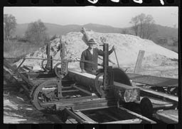 Black and white photo of a man working at a sawmill.